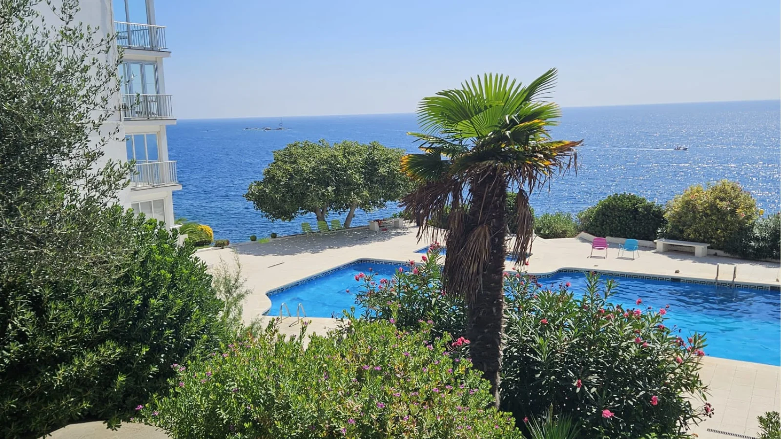 Piscine bordée de palmiers et mer en arrière-plan à Rosas