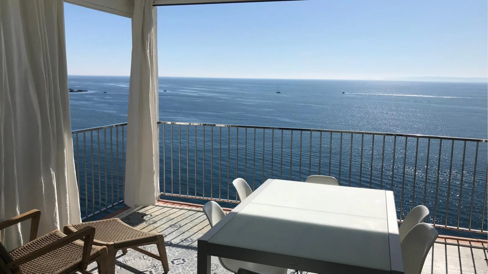 Terrasse vue mer à Rosas, avec table et voilages blancs